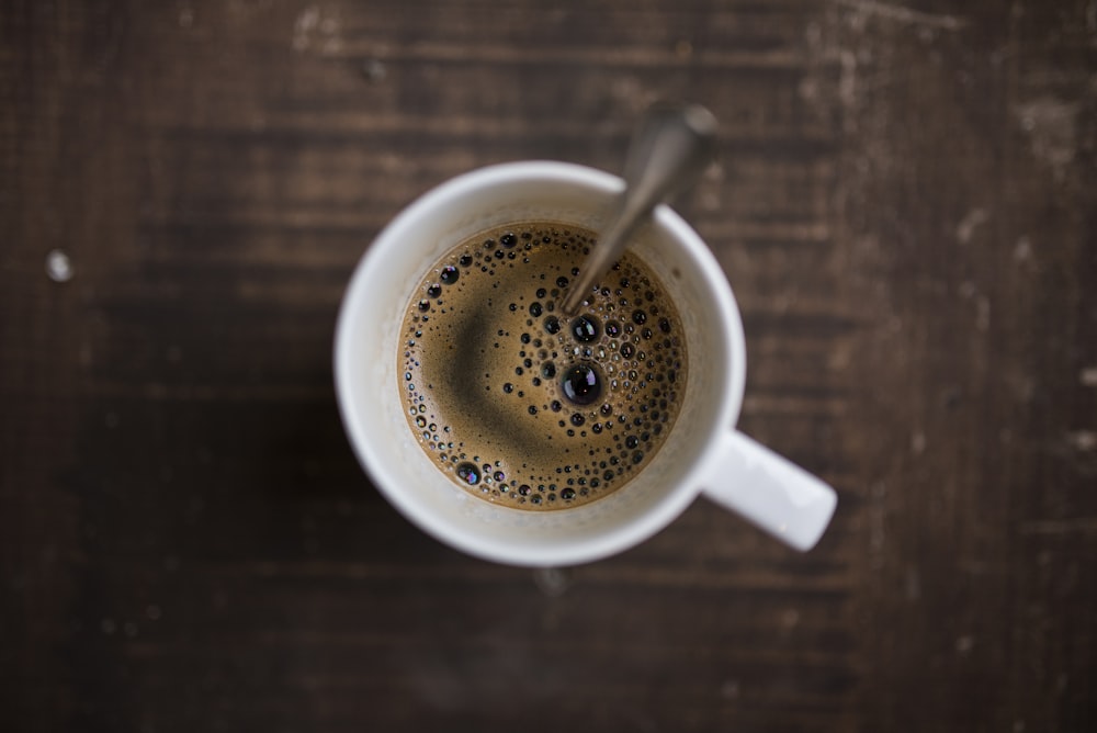 coffee on white ceramic mug with stainless steel spoon