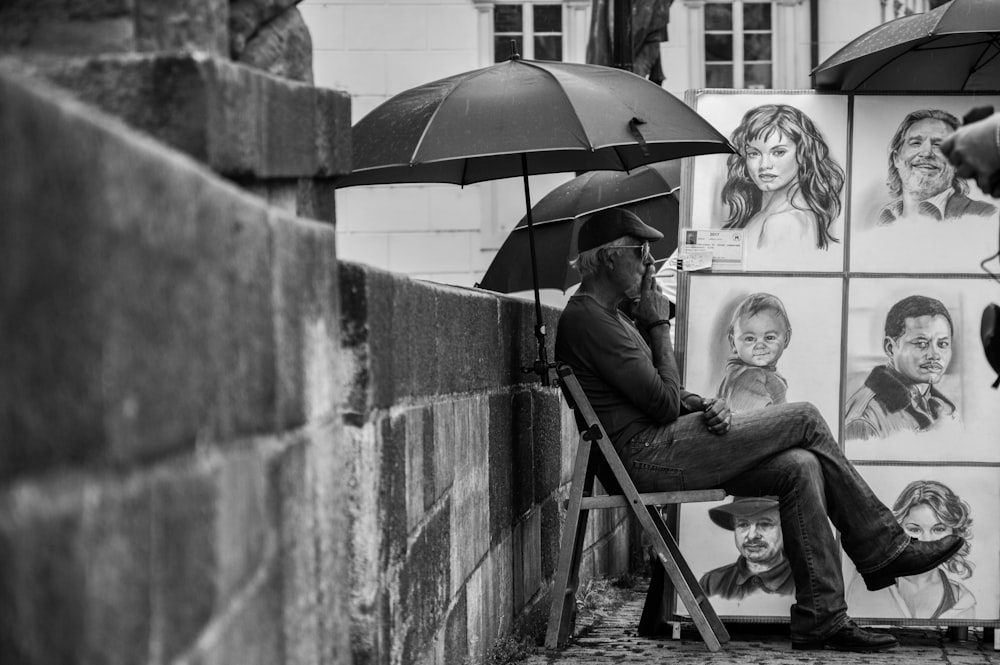 grayscale man selling paintings on street