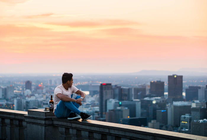 A person seated quietly beside city buildings, on those who quietly leave
