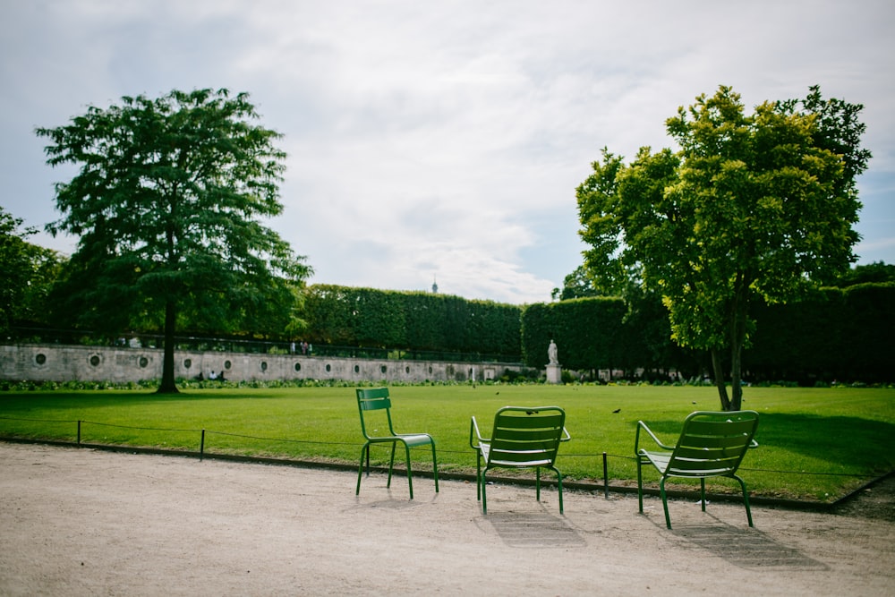 three green steel chairs near green field