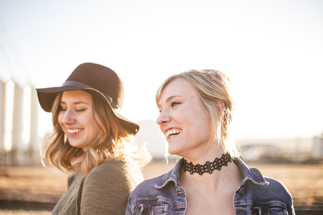 two woman taking a sideview selfie, Women with hat and choker