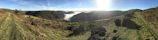 Panoramic view of a winding trekking trail disappearing into misty hills.