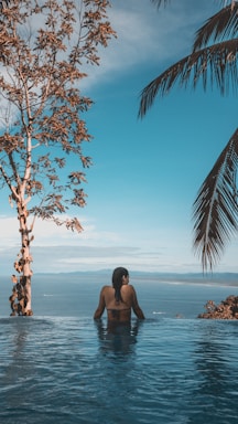 photography poses for pool & beach,how to photograph hotel pool with a pretty cool pacific ocean view.
 please credit me and follow me on instagram if you like my work. thanks!
 www.instagram.com/maxtscha; woman wearing black bikini tap swimming on body of water between trees