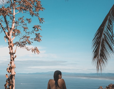 woman wearing black bikini tap swimming on body of water between trees