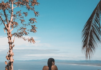 woman wearing black bikini tap swimming on body of water between trees