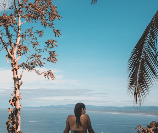 woman wearing black bikini tap swimming on body of water between trees