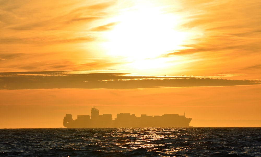 silhouette of ship on orange sunset
