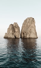 two beige rock formations on body of water