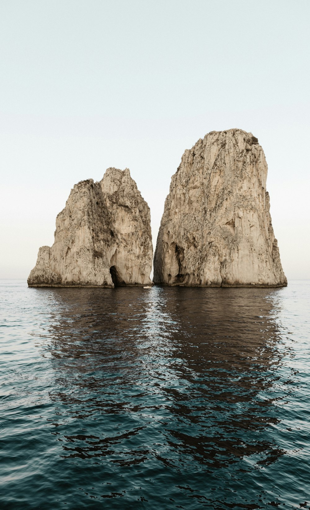 two beige rock formations on body of water