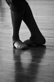 A close-up of a dancer’s feet mid-step on a polished wooden floor.