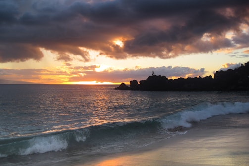 Sunset over a Pismo Beach oceanfront property with waves crashing nearby.