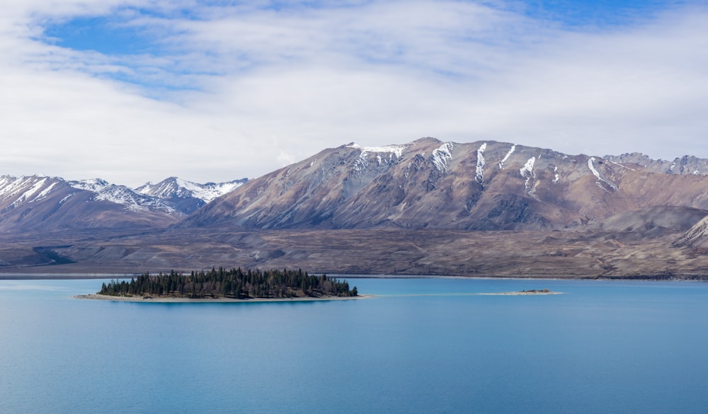 brown mountain near islet under blue sky