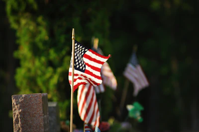 An American flag gently waving beside a field of white crosses marking graves of fallen soldiers.