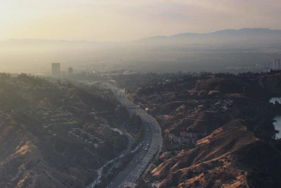 A panoramic view of a sprawling highway project weaving through a mountainous landscape at sunrise.
