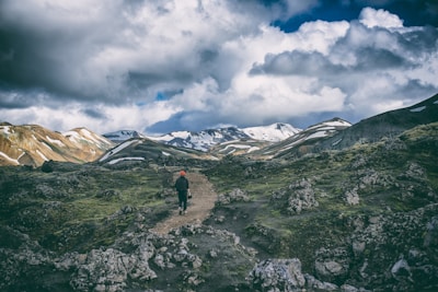 person in black suit walking on brown road
