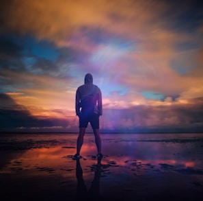 A man standing triumphant on a beach in New Romney while looking out into the water