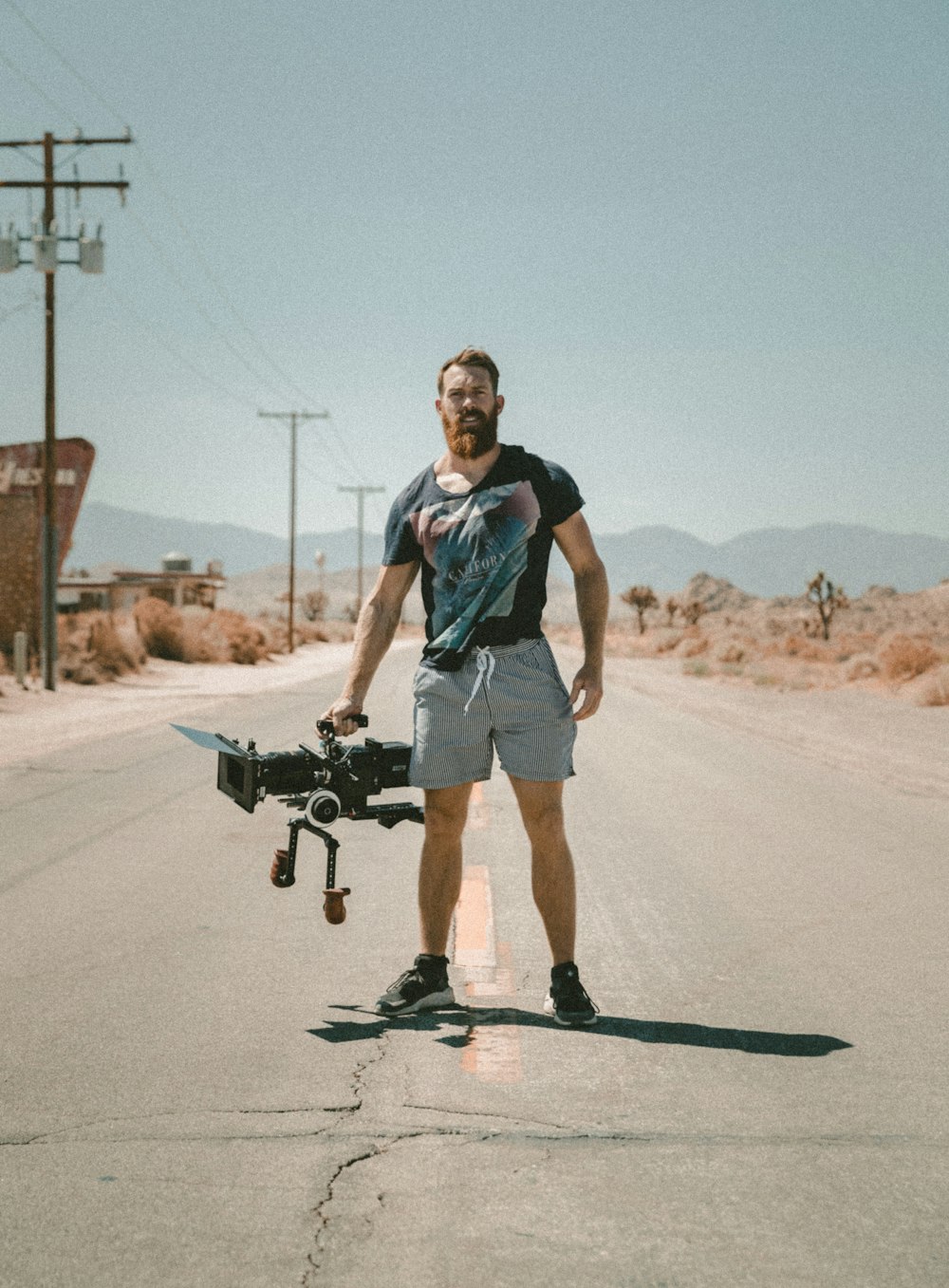 man holding camera standing on road during daytime