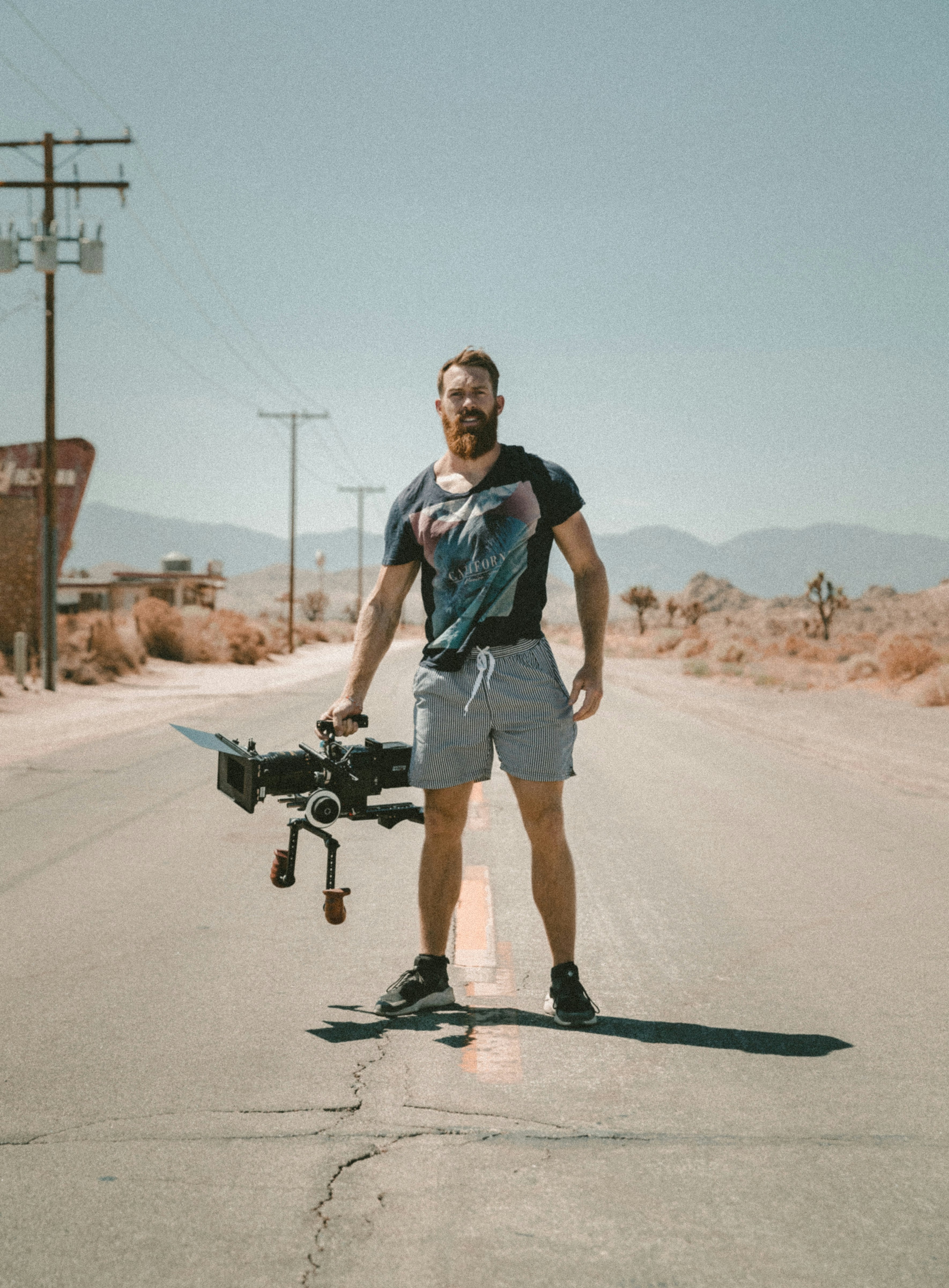 man holding camera standing on road during daytime