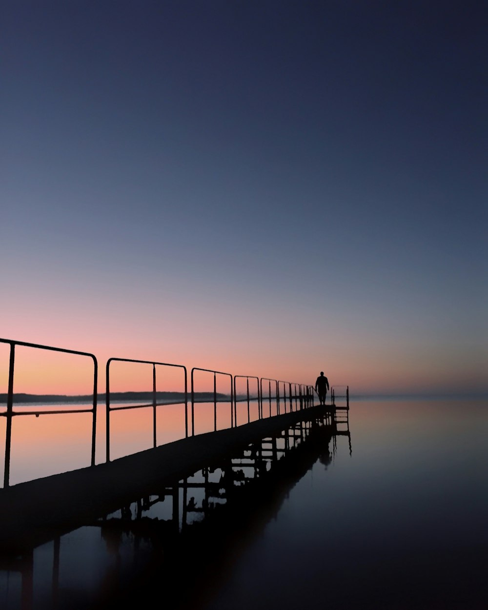 silhouette photo of person standing on dock