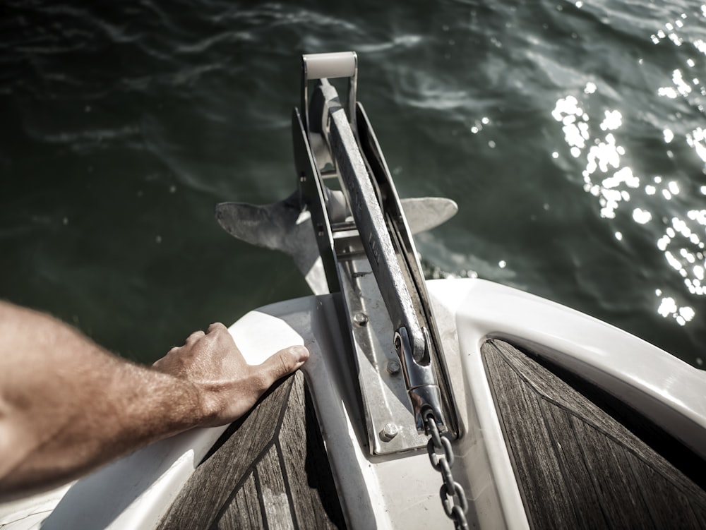 person holding the edge of the boat near anchor