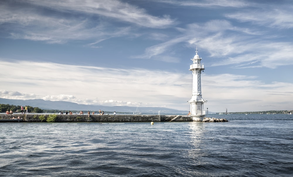 white lighthouse near body of water under blue sky during daytime