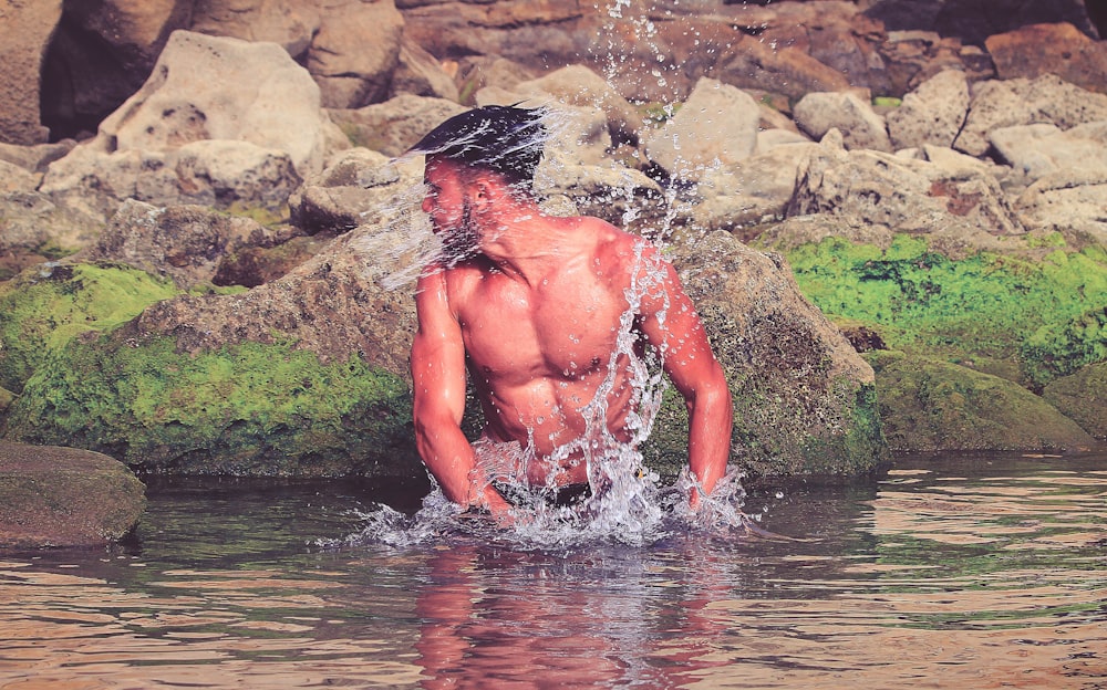 homme aux seins nus dans l’eau pendant la journée