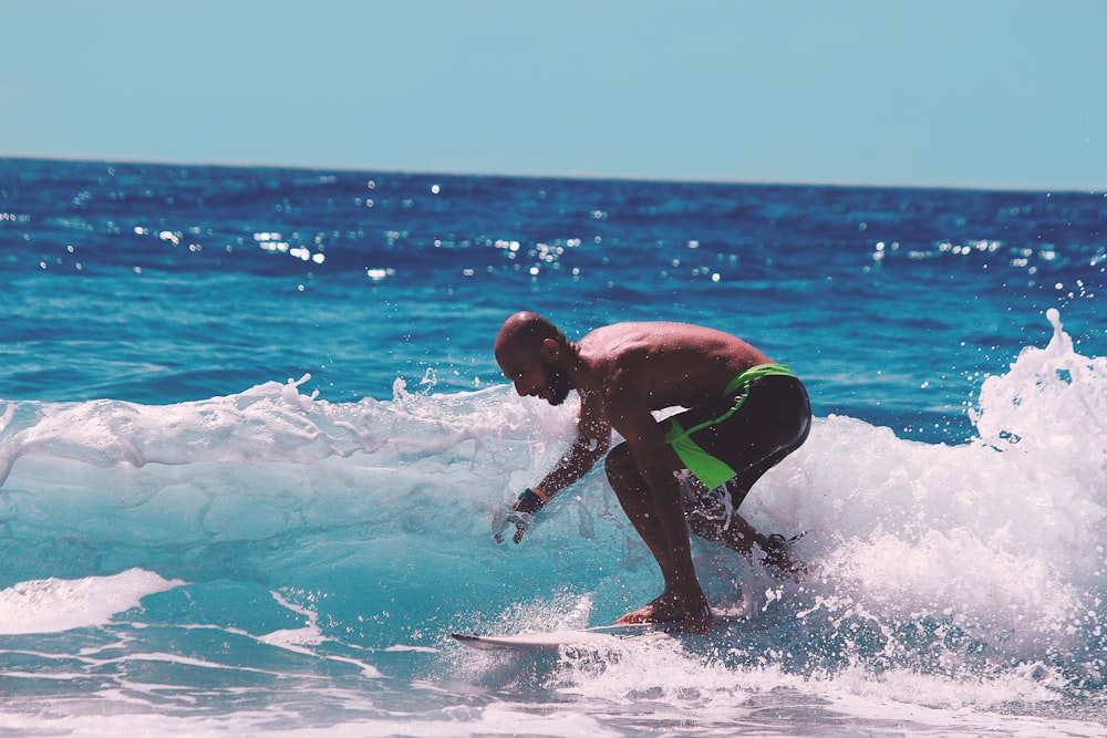 man in green and black shorts surfing on sea waves during daytime