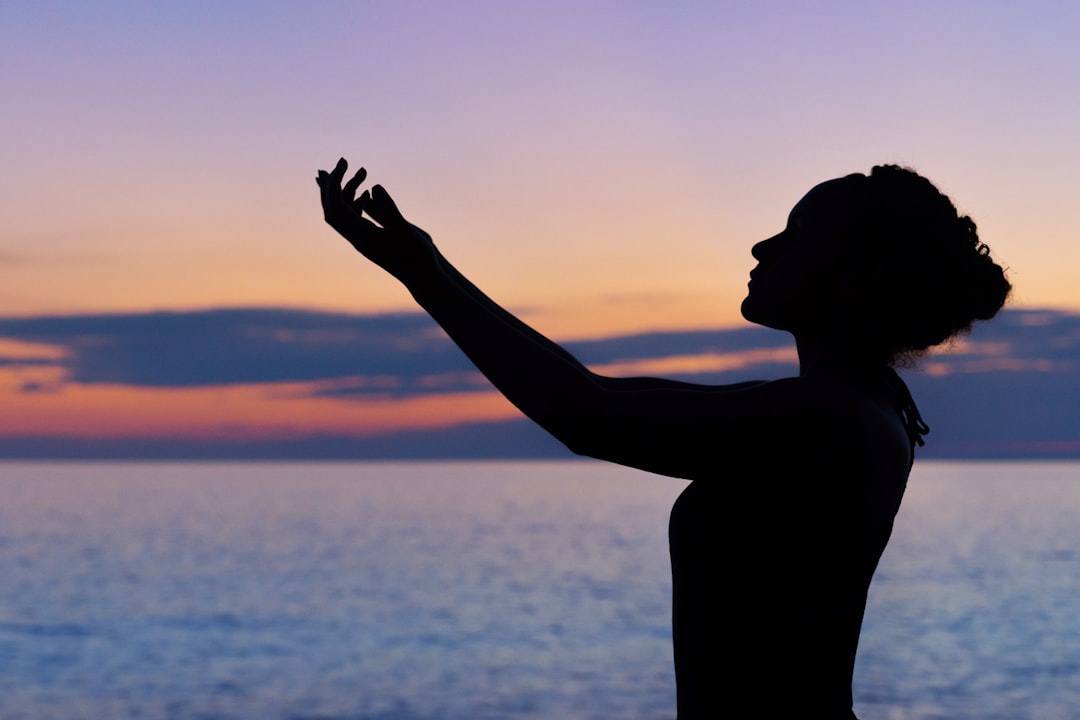 The silhouette of a woman doing yoga by the water during sunrise or sunset in Saint Joseph