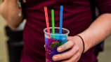 Close-up of a vibrant slush cup with bright red and blue layers topped with a straw.