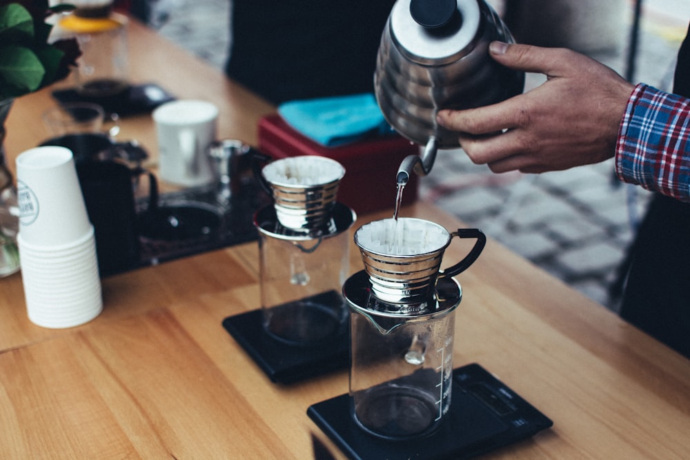 person holding gray stainless steel kettle