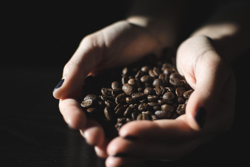 Pila di chicchi di caffè sulla mano della persona