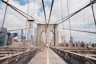 people walking on grey concrete bridge under white clouds during daytime