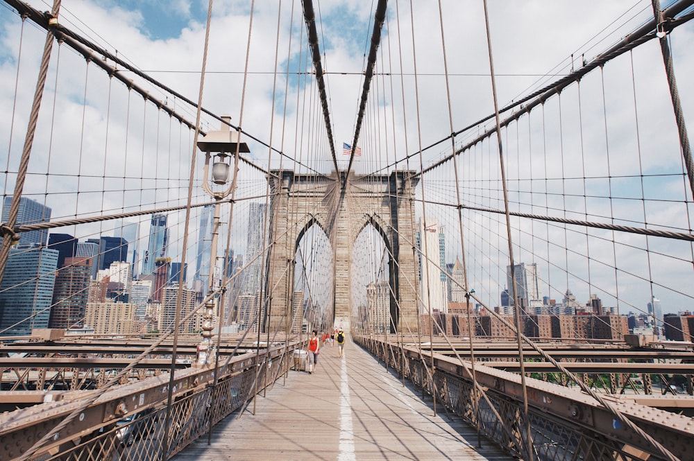 people walking on grey concrete bridge under white clouds during daytime