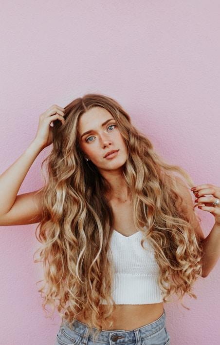 woman standing next to pink wall while scratching her head