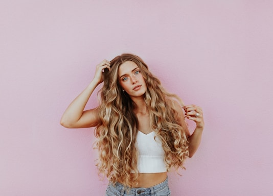 woman standing next to pink wall while scratching her head