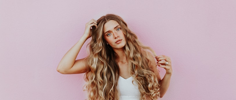 woman standing next to pink wall while scratching her head