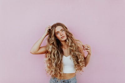 woman standing next to pink wall while scratching her head woman google meet background