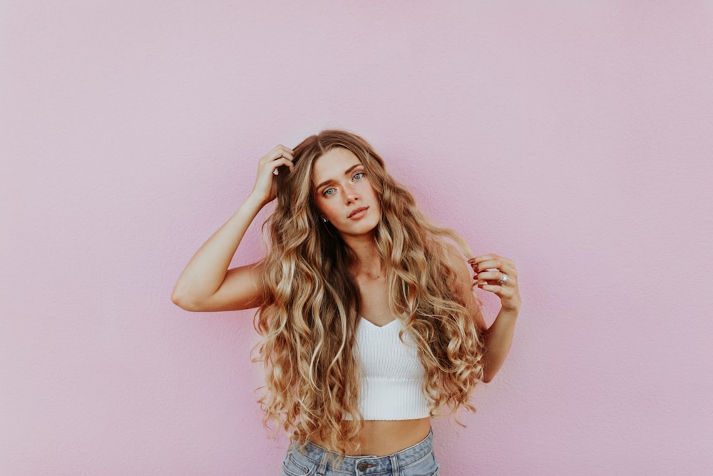 woman standing next to pink wall while scratching her head