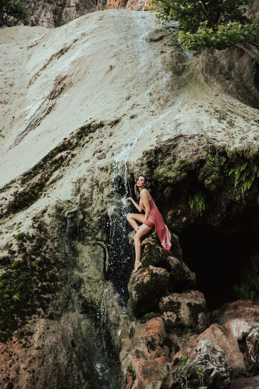 donna che si siede sulla roccia sotto le cascate