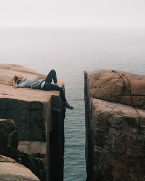 woman lying on top of cliff