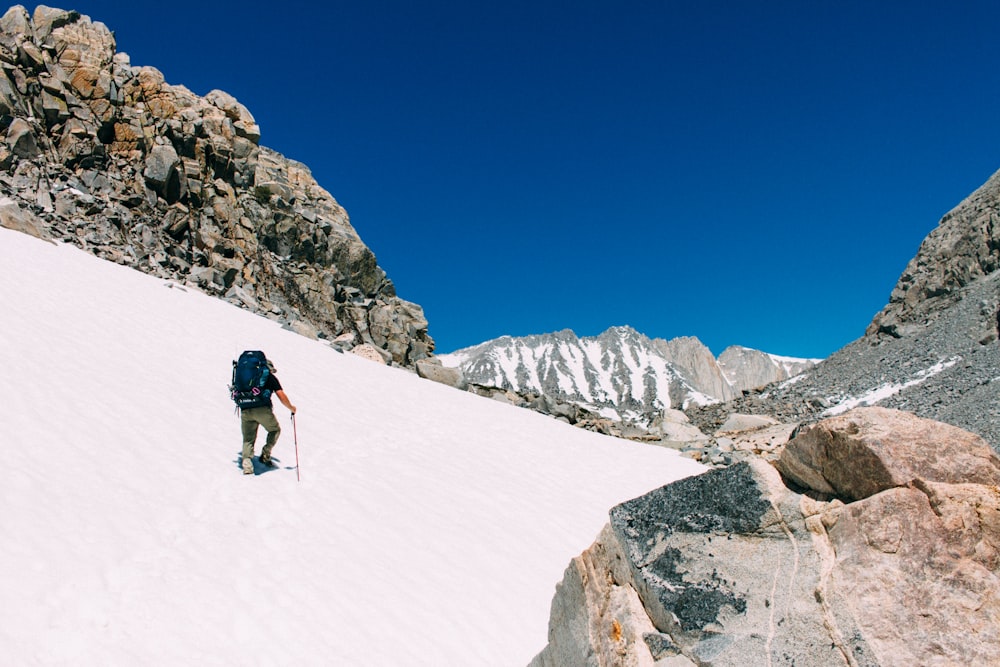 man in black jacket and blue denim jeans walking on snow covered ground during daytime