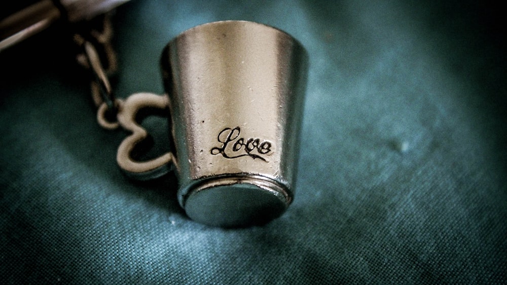 closeup photo of silver-colored love mug pendant