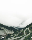 A misty mountain pass in Asia with a van winding through lush green hills.