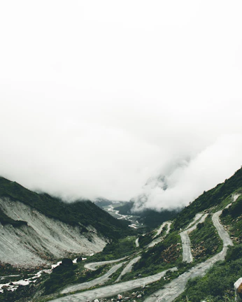 A misty mountain pass in Asia with a van winding through lush green hills.