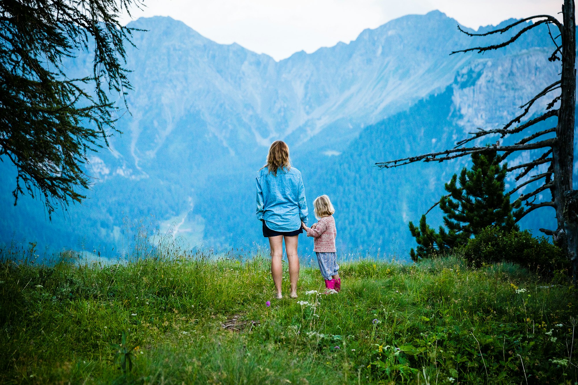 Woman and little girl standing toward a mountainside 