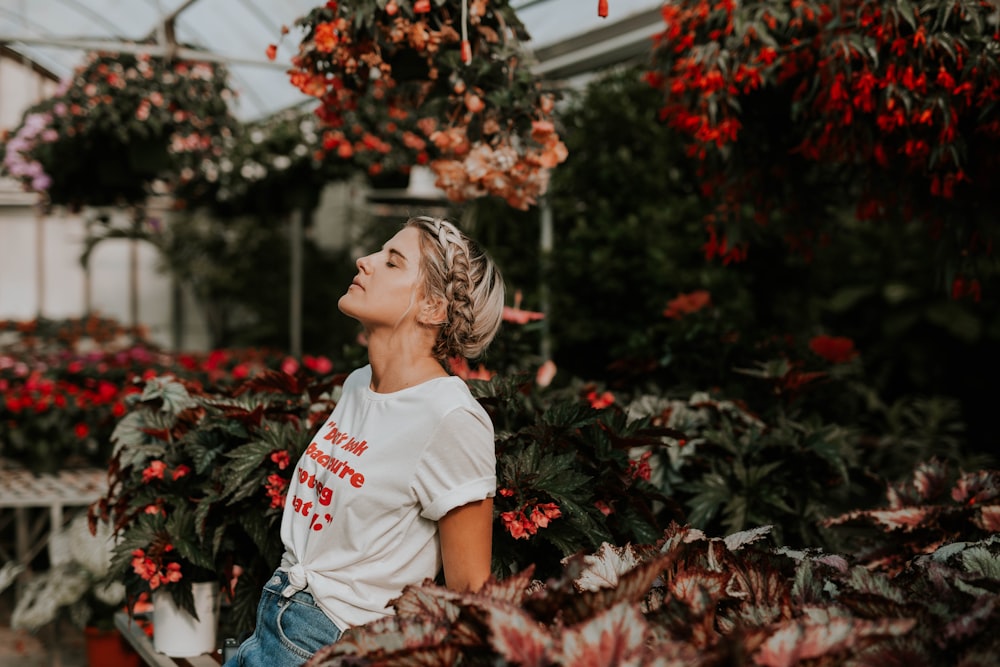 mujer con camisa blanca de pie cerca de la flor