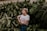 woman in white shirt standing and surrounded by green plants