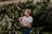 woman in white shirt standing and surrounded by green plants