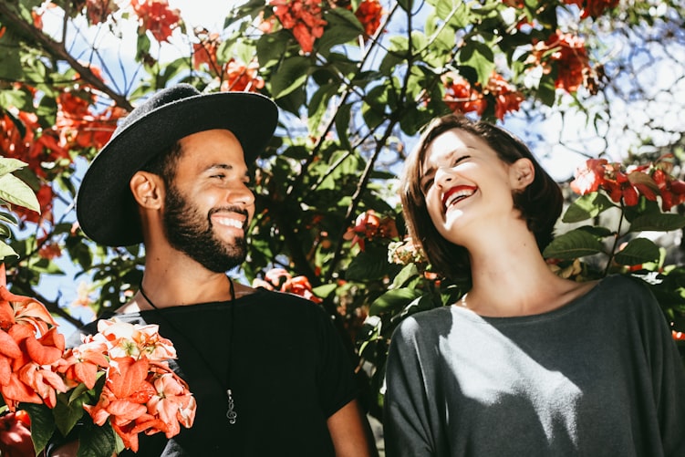 man and woman surrounded by red and green floral trees during daytime