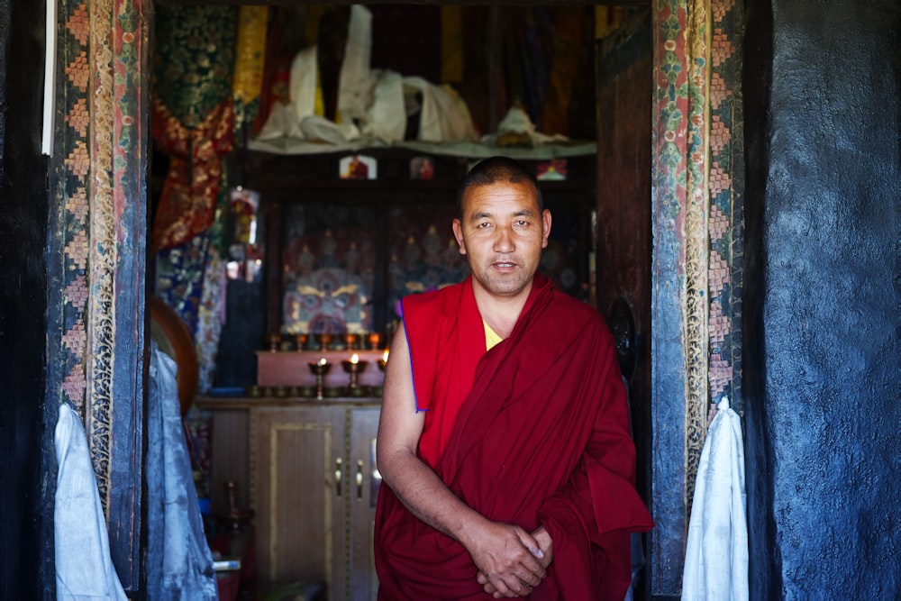 Buddhistischer Mönch steht hinter braunem Holzschrank